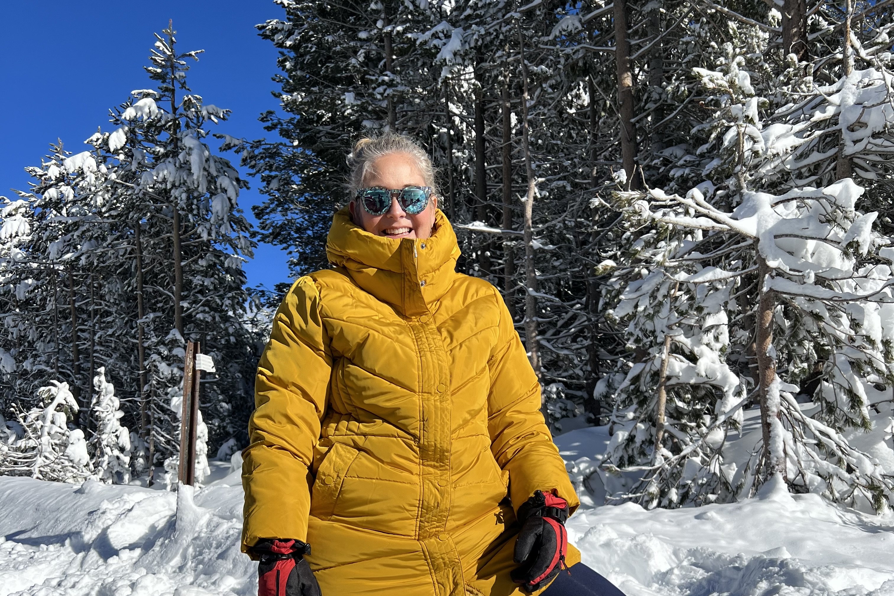 Angie poses for a photo in front of snow covered pines in Arnold, California