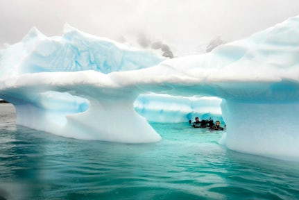 Scuba divers in an iceberg in Antarctica