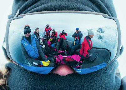 Groups of Antarctic tourists in a zodiac reflected in a pair of goggles