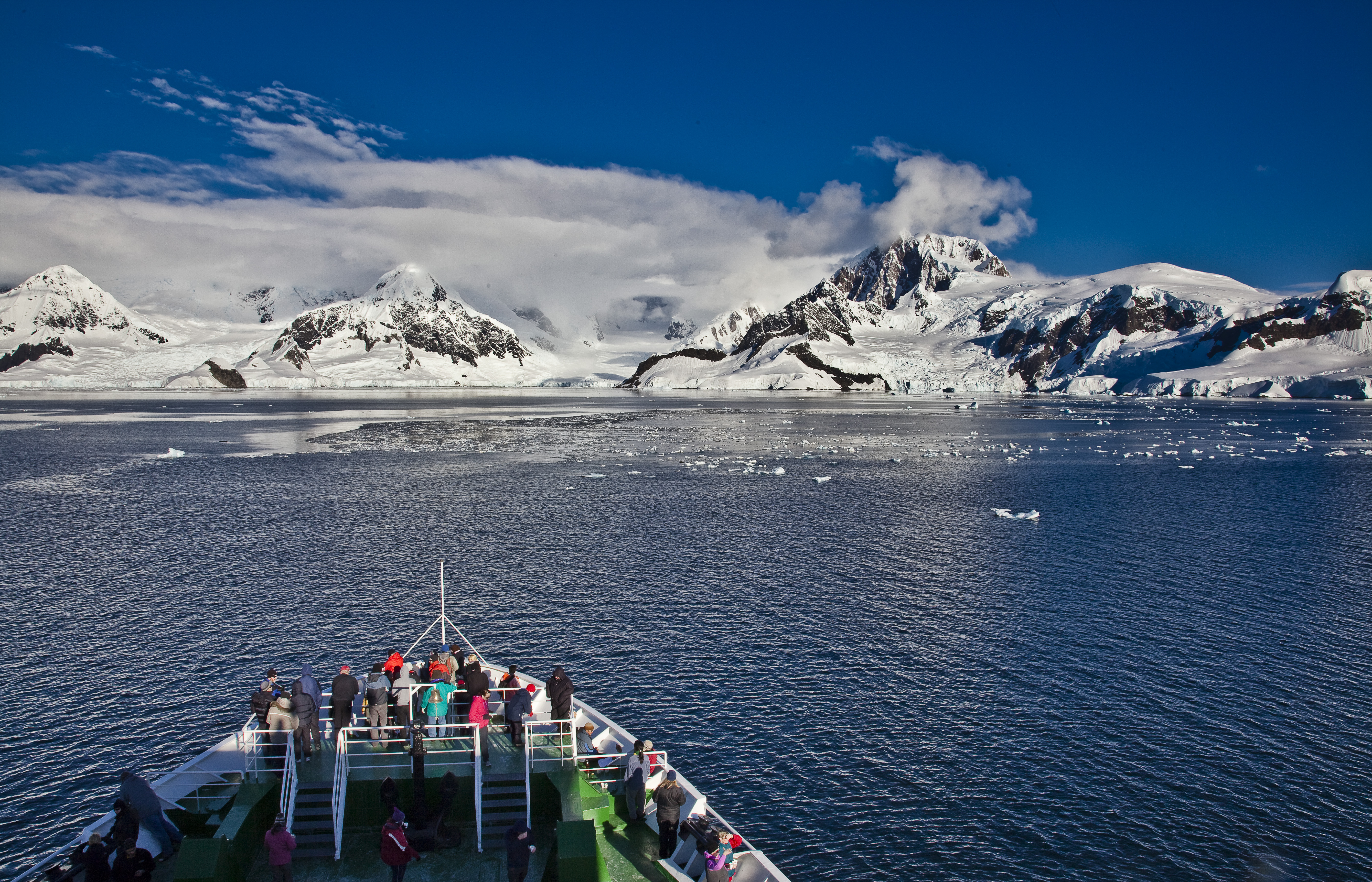 Bow of vessel and travellers sailing through the channels of the Antarctic Peninsula