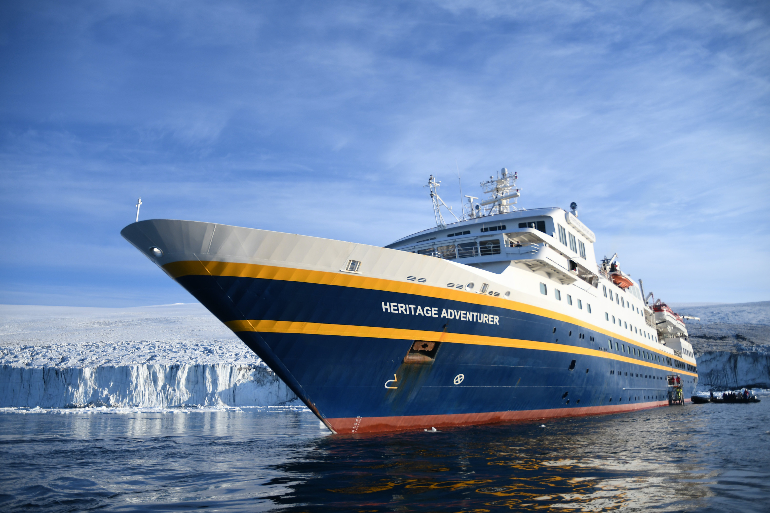 MS Adventurer in the Ross Sea, anchored near an ice shelf with passengers in a nearby zodiac