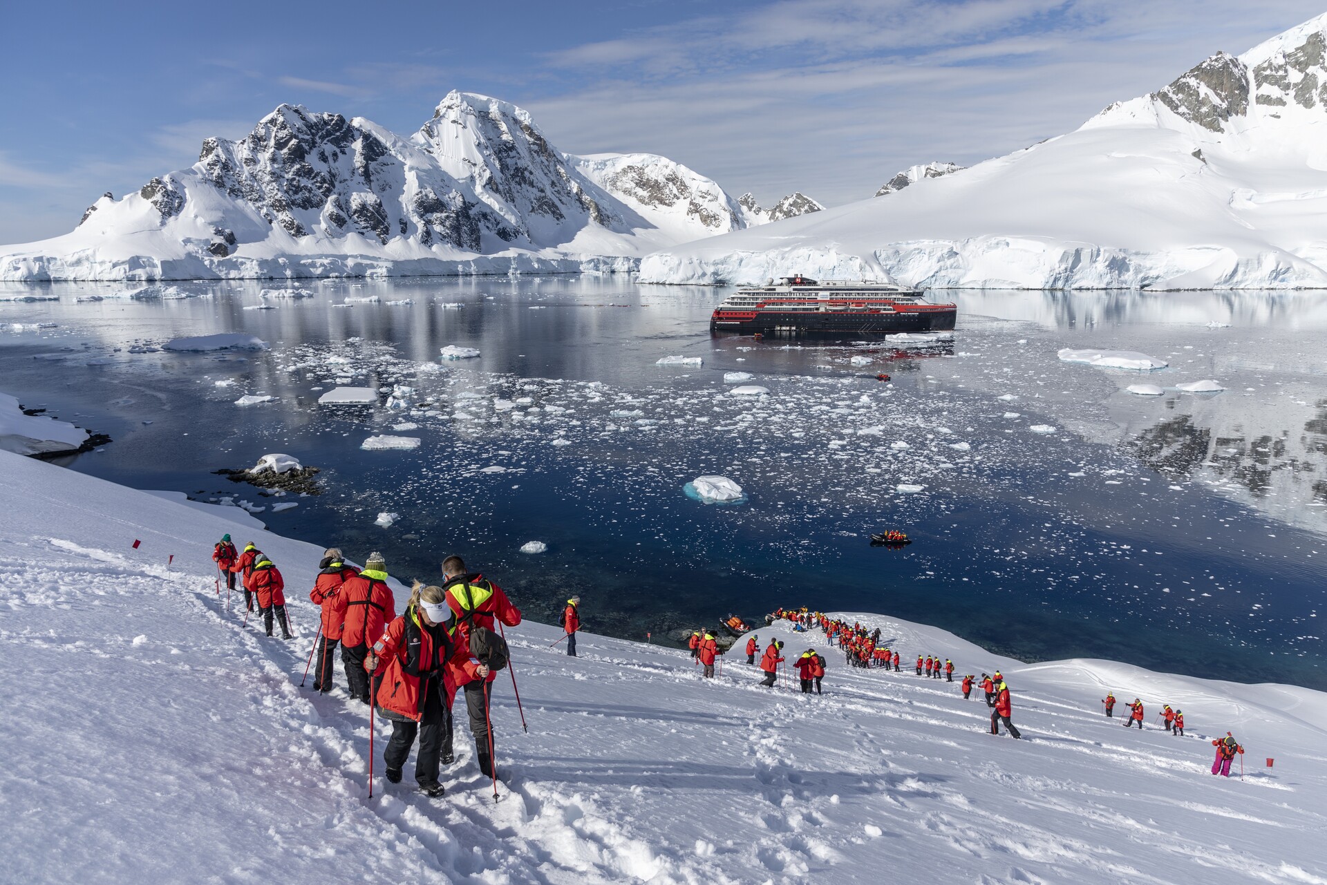 A group snowshoes in Orne Harbour, Antarctica, with a ship in the background
