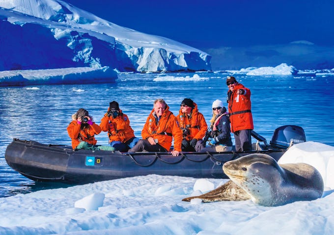 Guests exploring by zodiac take photos of a leopard seal in Dallmann Bay