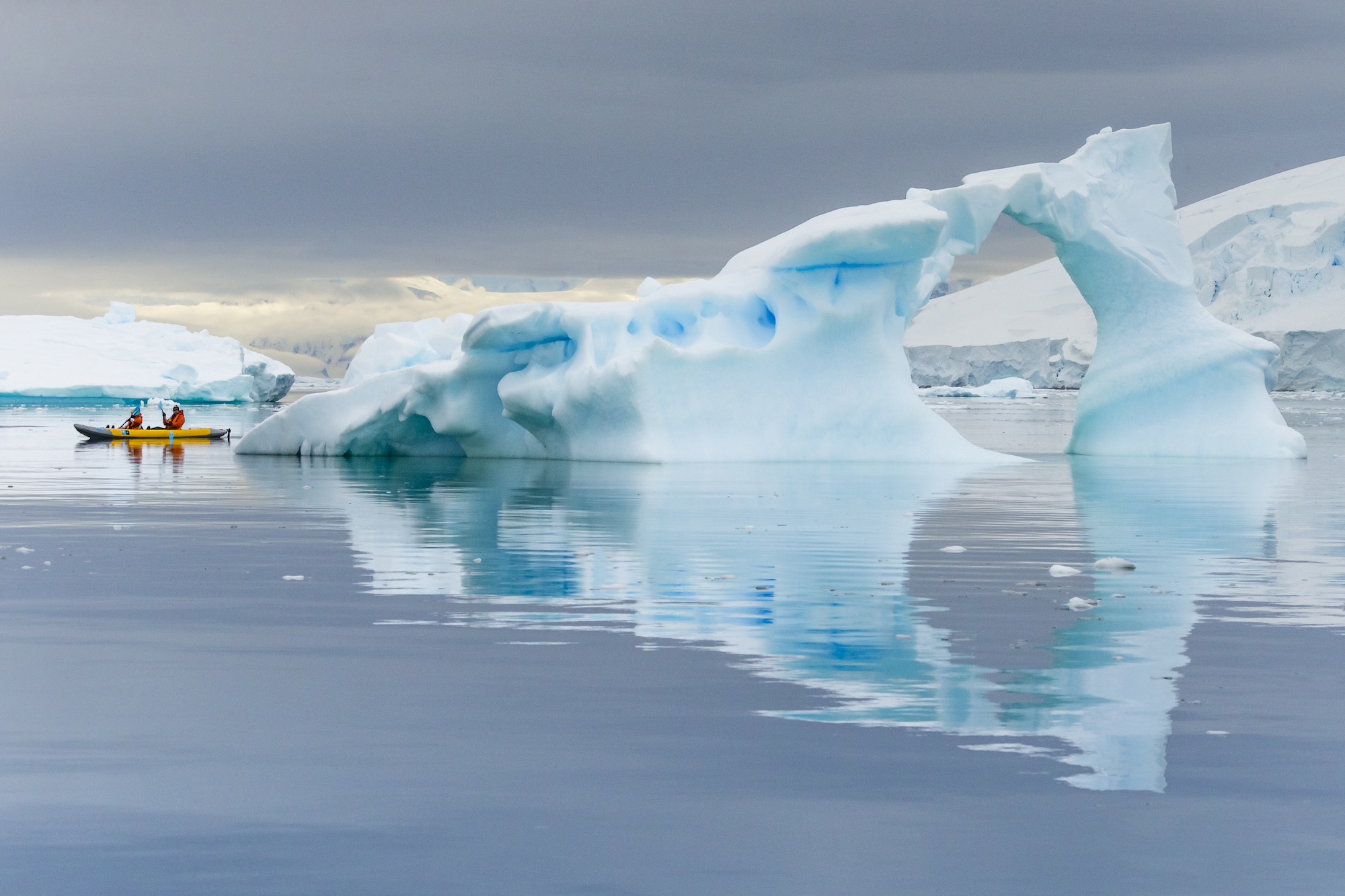 Two people kayak among Neko Harbour's sculptural icebergs in Antarctica