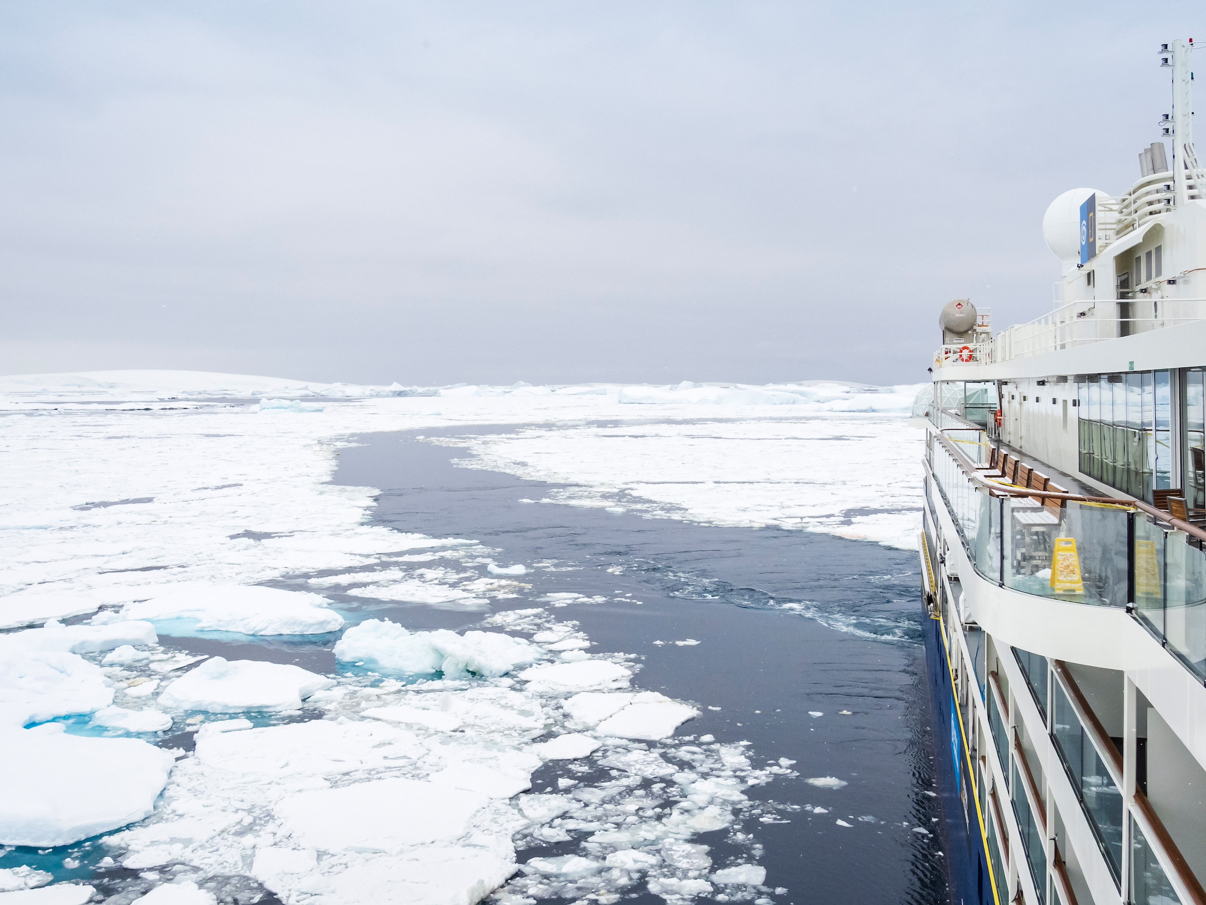 A ship is shown navigating the pack ice in Antarctica near Booth Island 