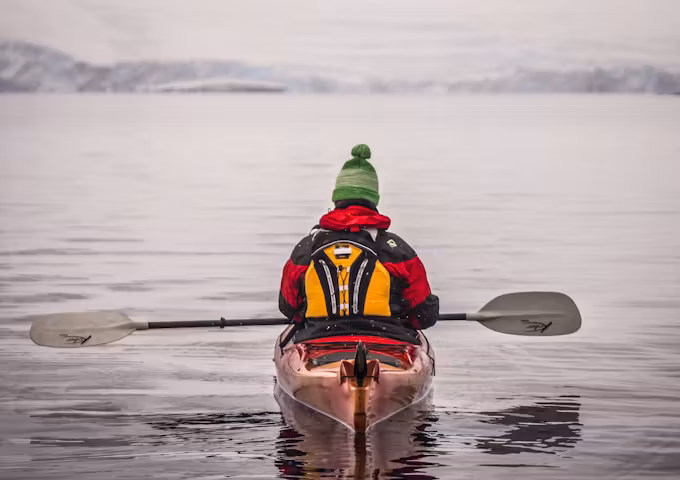 A kayaker glides across placid polar waters in Antarctica
