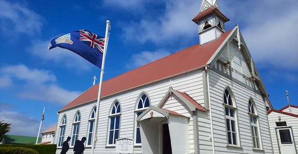 A flag flies in from the of the whitewashed catholic church in Stanley on the Falkland Islands