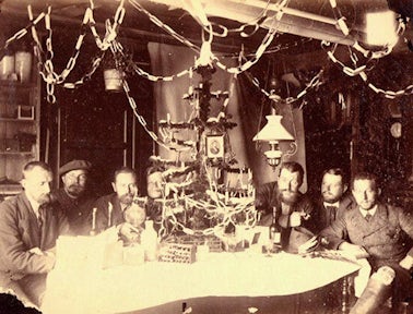 The German expedition of 1882/3 led by Dr Schrader gather around a table under bunting to celebrate Christmas on South Georgia