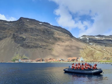 Expedition cruise passengers zodiac cruising  past the abandoned and rusting remains of the whaling station at Stromness harbour, South Georgia