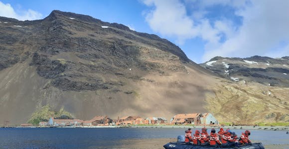 Expedition cruise passengers zodiac cruising  past the abandoned and rusting remains of the whaling station at Stromness harbour, South Georgia