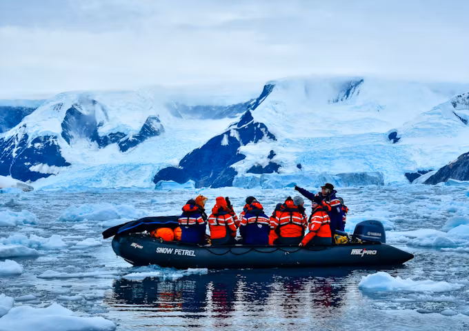 Passengers glide past an iceberg on a zodiac cruise in Antarctica