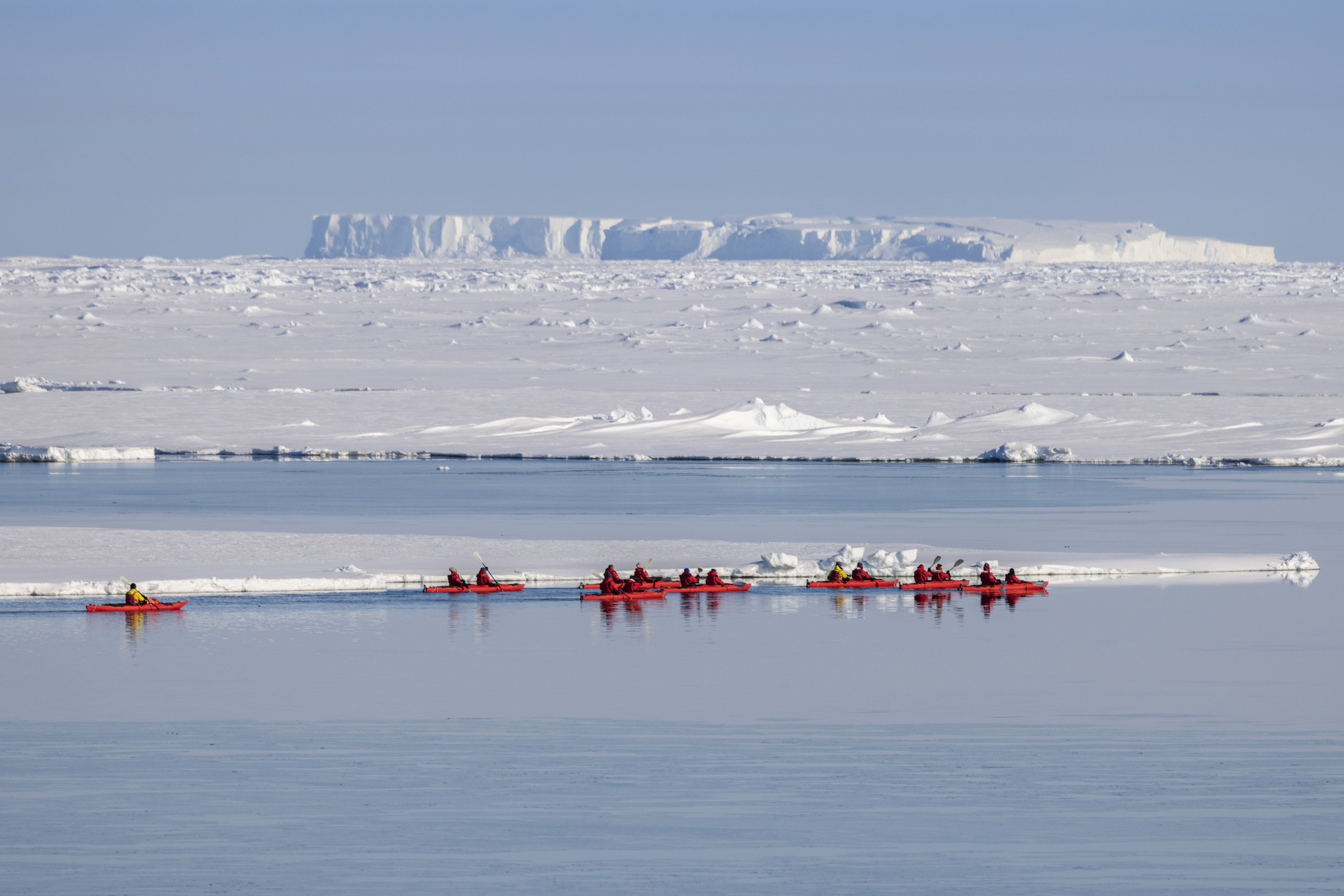 A group kayaks in front of tabular icebergs in the Weddell Sea