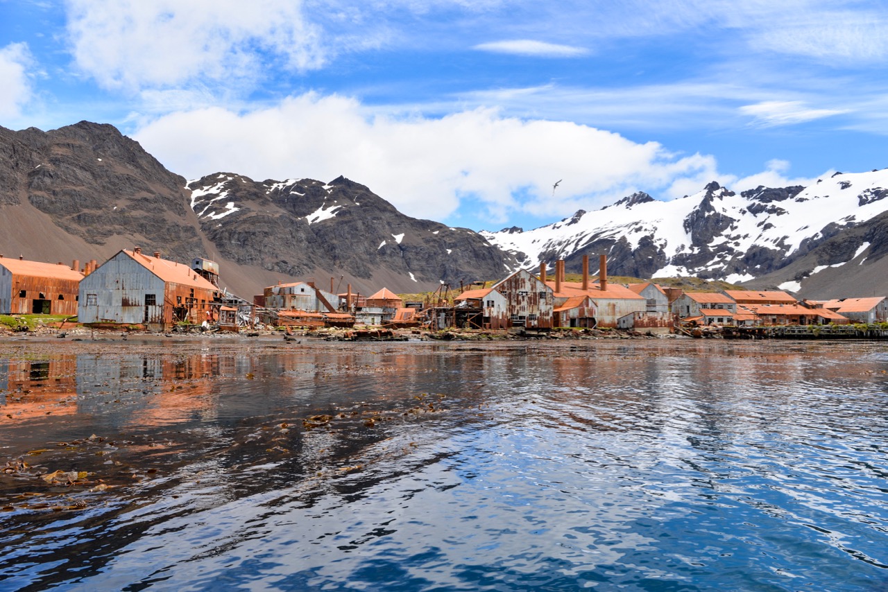 Rusting ruins of the abandoned Stromness Harbour whaling station on South Georgia, with mountains in the background