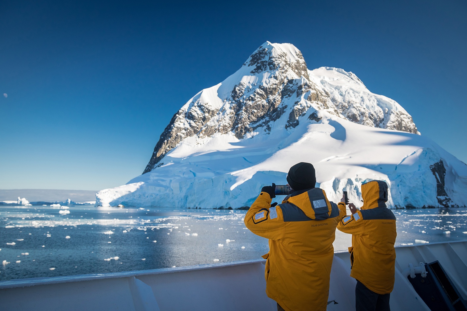 Guests take pictures of icy landscapes in the Lemaire Channel, Antarctica