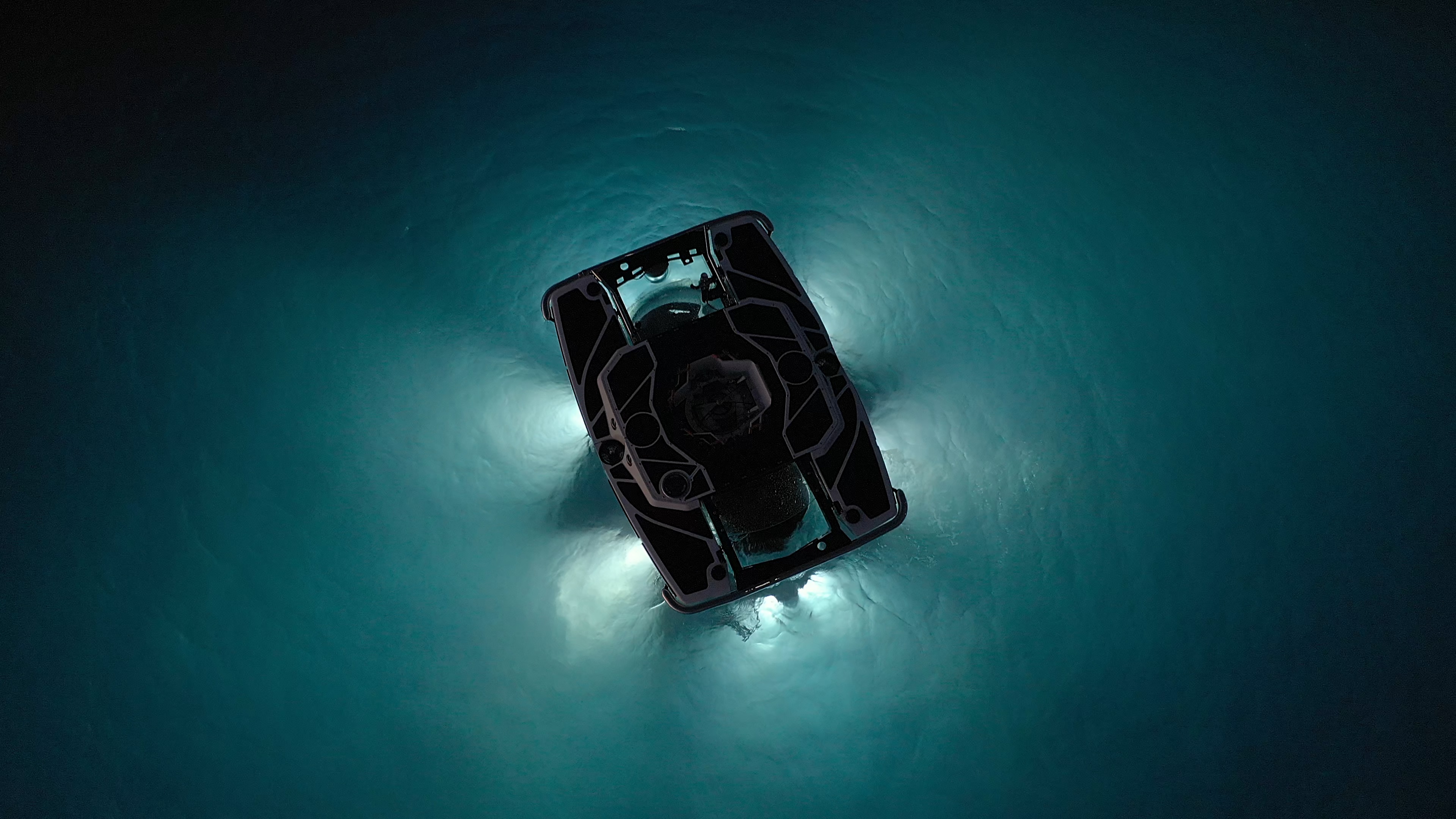 An eerie interplay of light and dark forms outside a submarine sinking into the sea