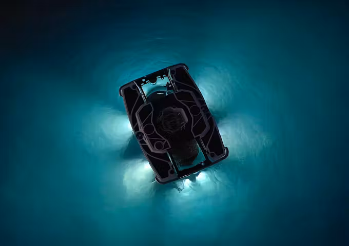 An eerie interplay of light and dark forms outside a submarine sinking into the sea