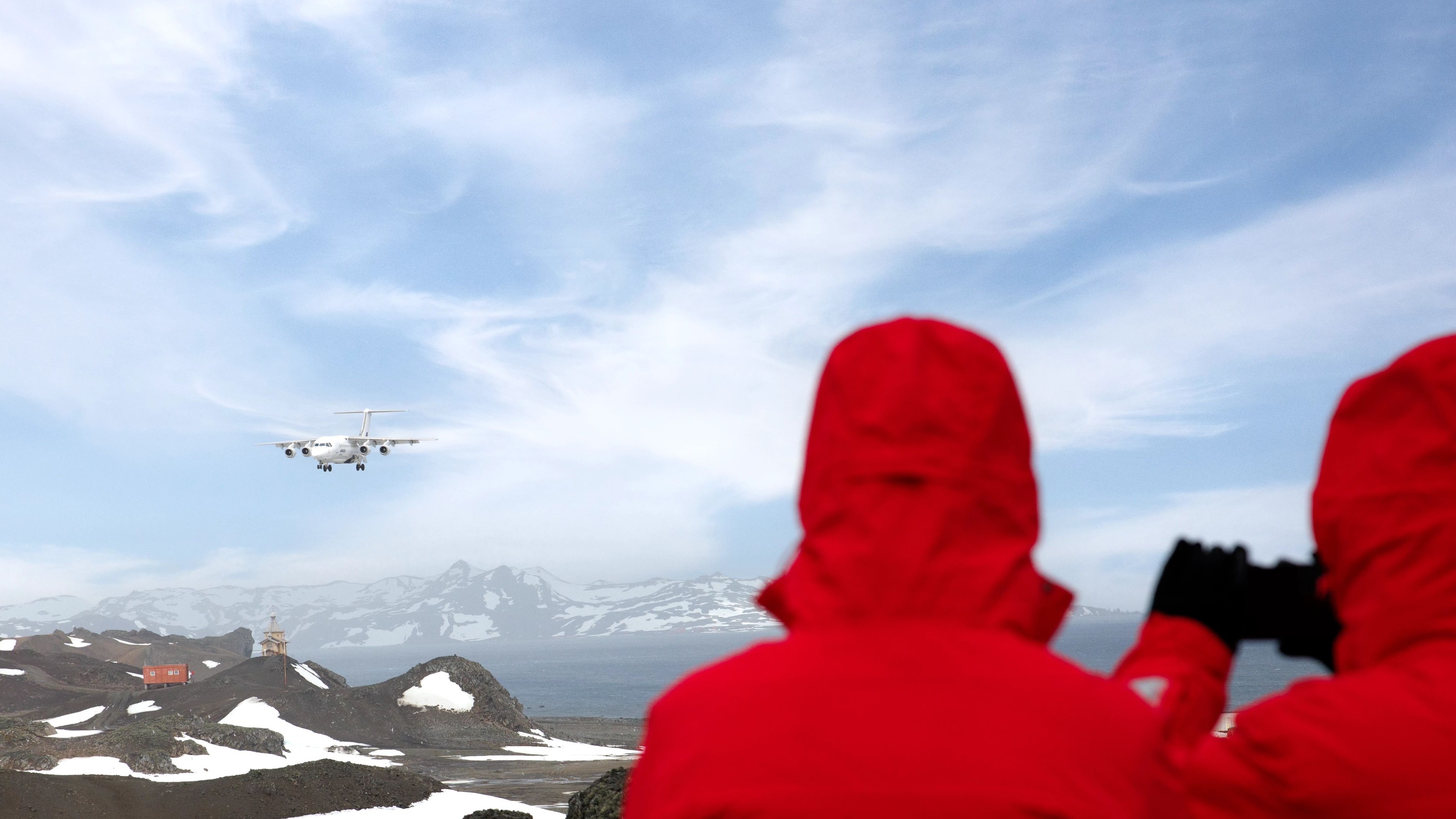 Passengers watch as a plan lands on King George Island, Antarctica