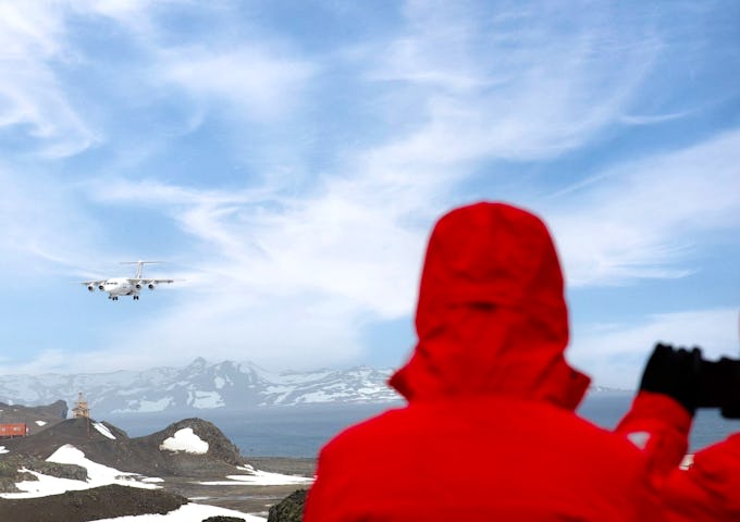 Passengers watch as a plan lands on King George Island, Antarctica