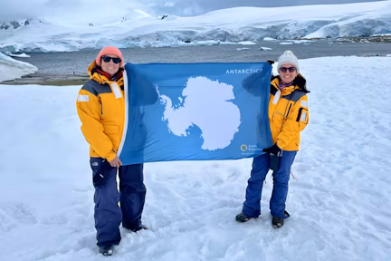 Two tourists flying the Antarctic flag on the 7th Continent