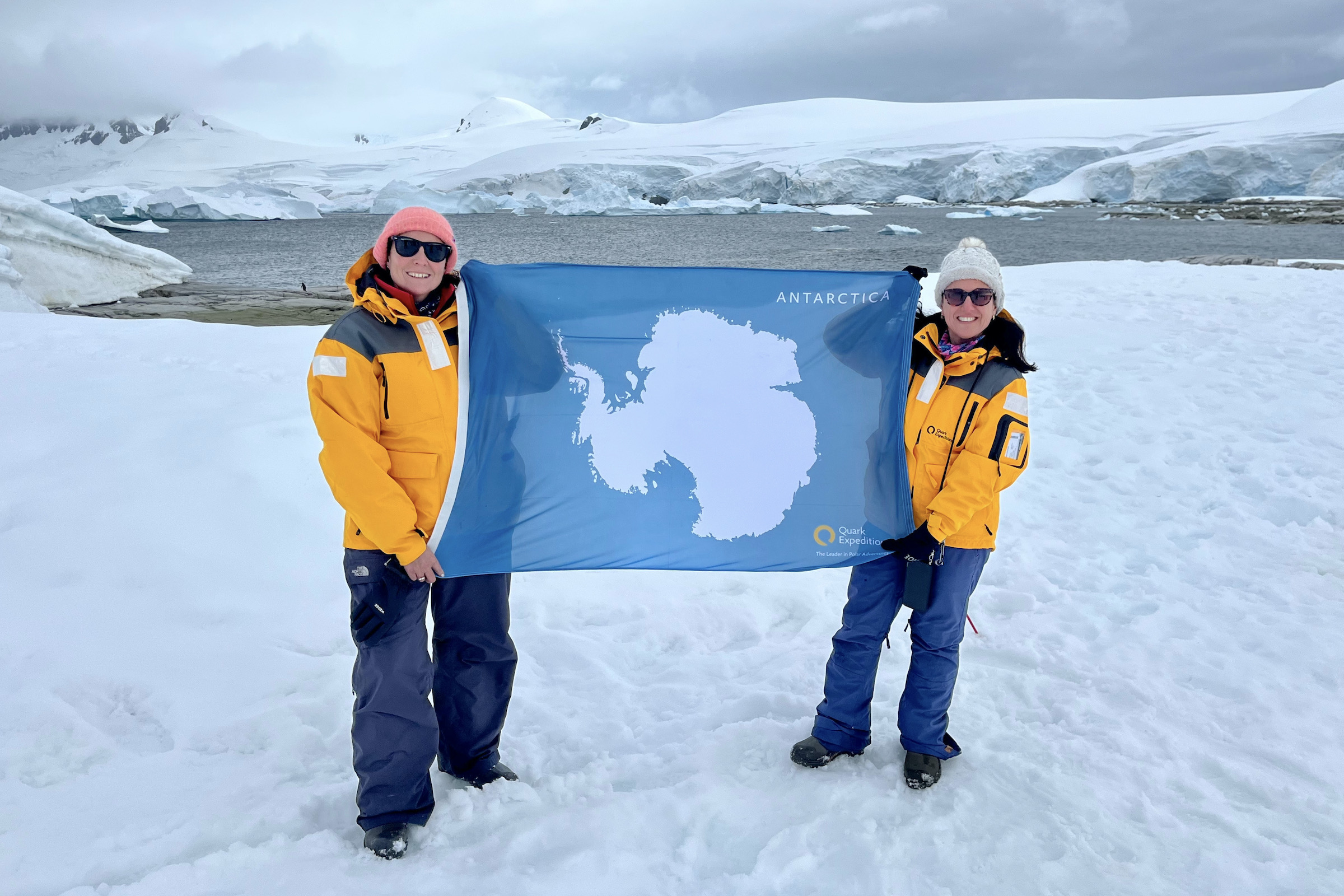 Two tourists flying the Antarctic flag on the 7th Continent