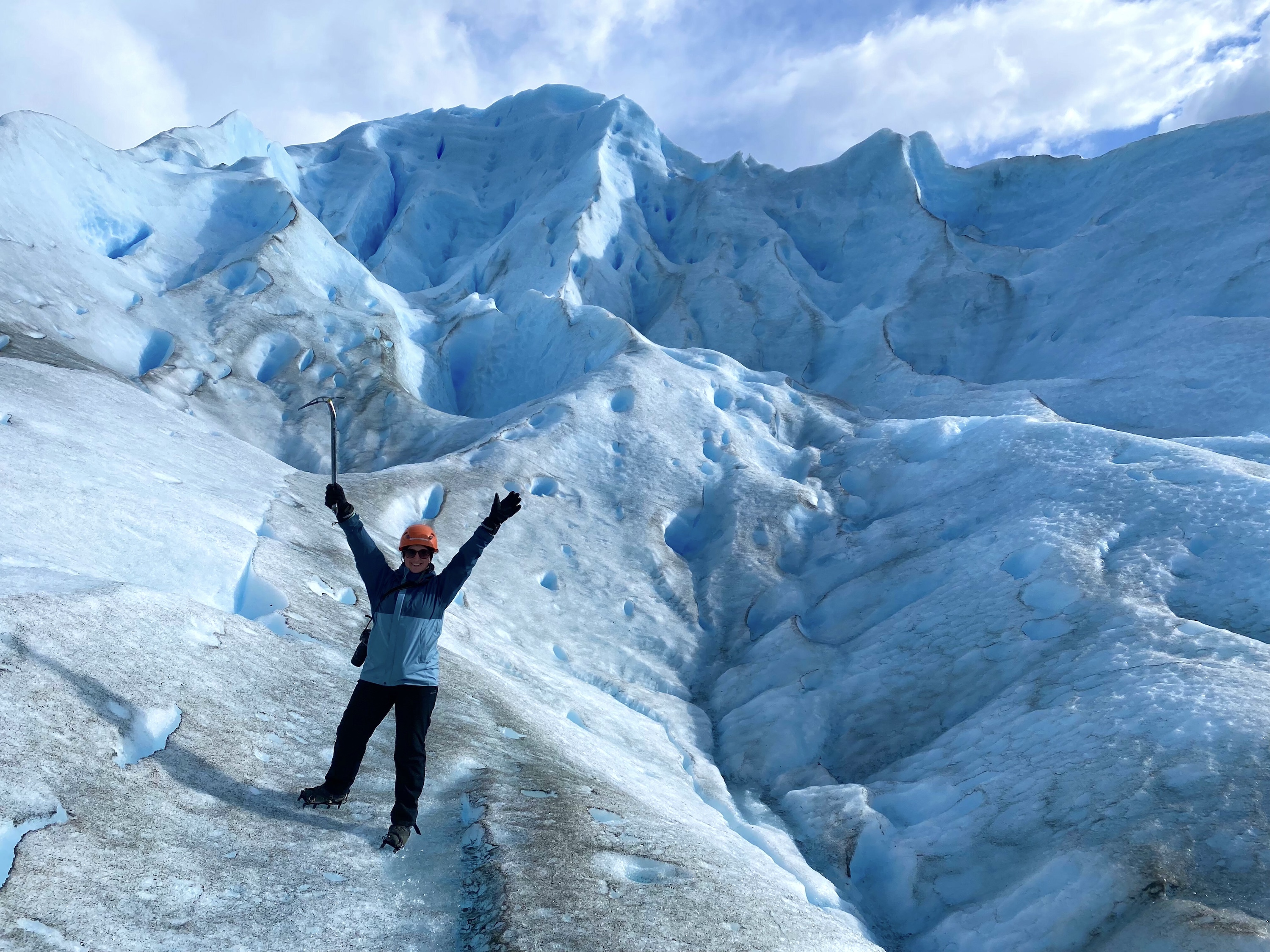 Carys from Swoop celebrates with her hands in the air as she ice hikes at Perito Moreno Glacier