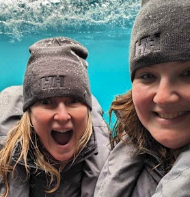Two women look ecstatic as they explore underwater in Antarctica in a submarine