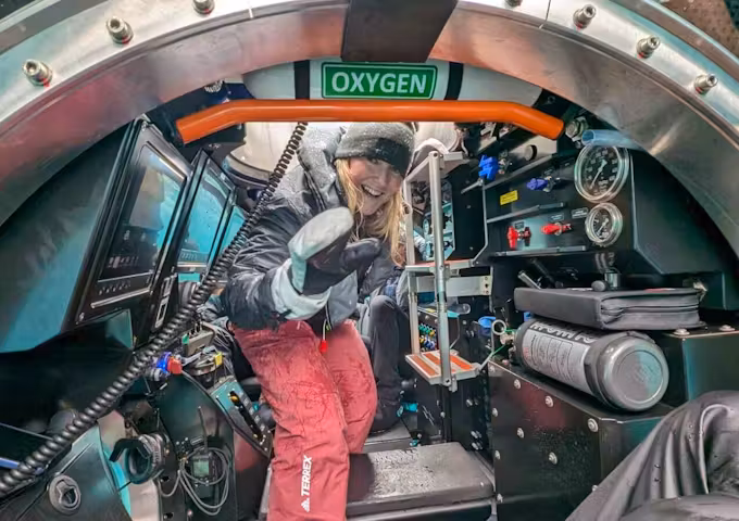 A women waves as she enters a submarine in Antarctica