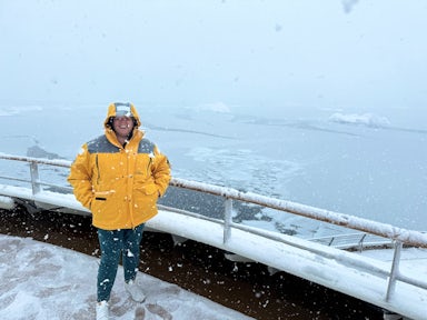 A woman stands out in flurries of snow on the deck of an Antarctic ship