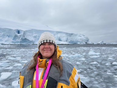 Swoop team member Julie smiles for the camera in front of an icy Antarctic backdrop