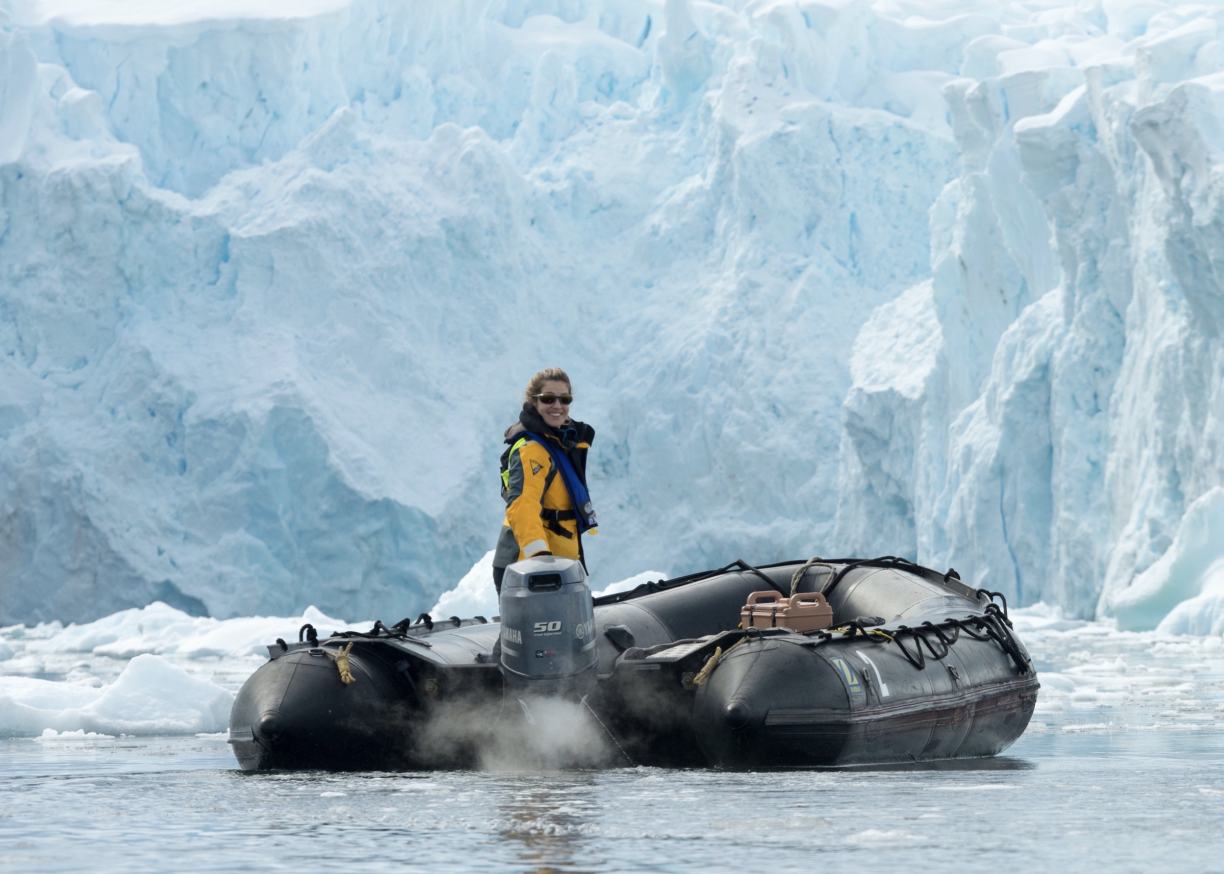 Antarctic expedition guide piloting a zodiac near an iceberg