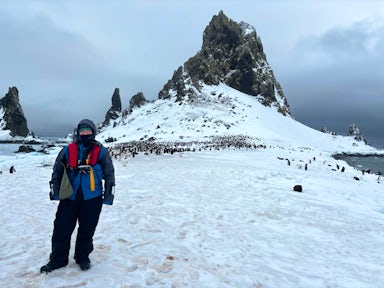 Lu, an Antarctic sales team member, poses in front of a penguin rookery in Antarctica