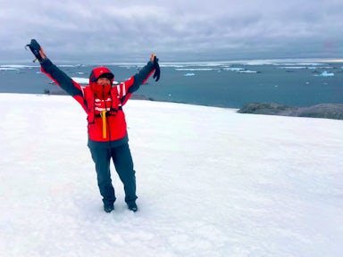 A woman holds her hands up to the sky in Antarctica