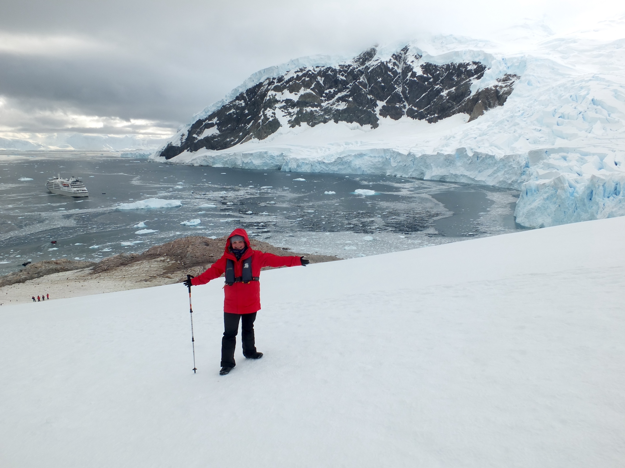 Mel from Swoop stands with her arms spread open among the snow of Neko Harbour