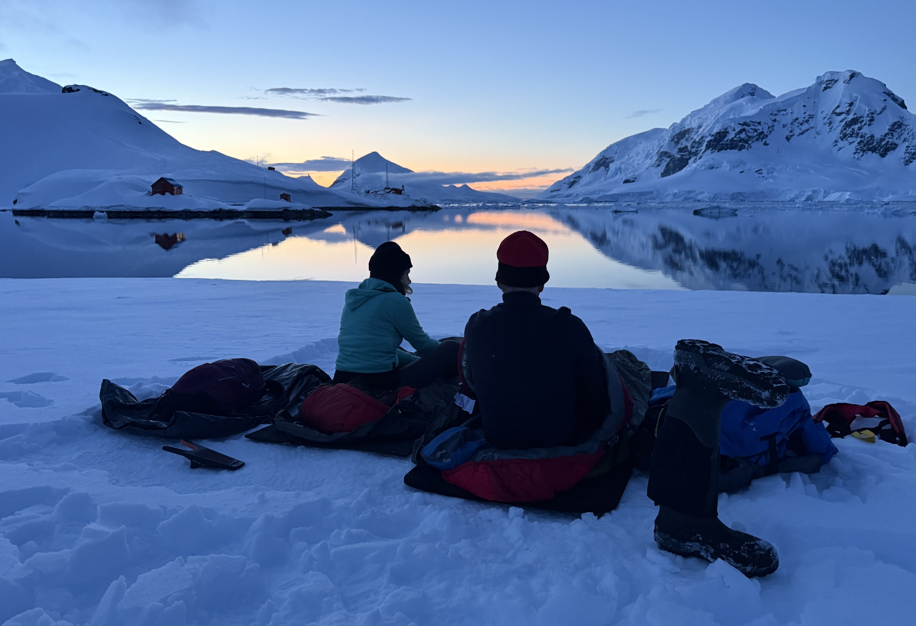Two people enjoy the sunset while camping on Antarctica 