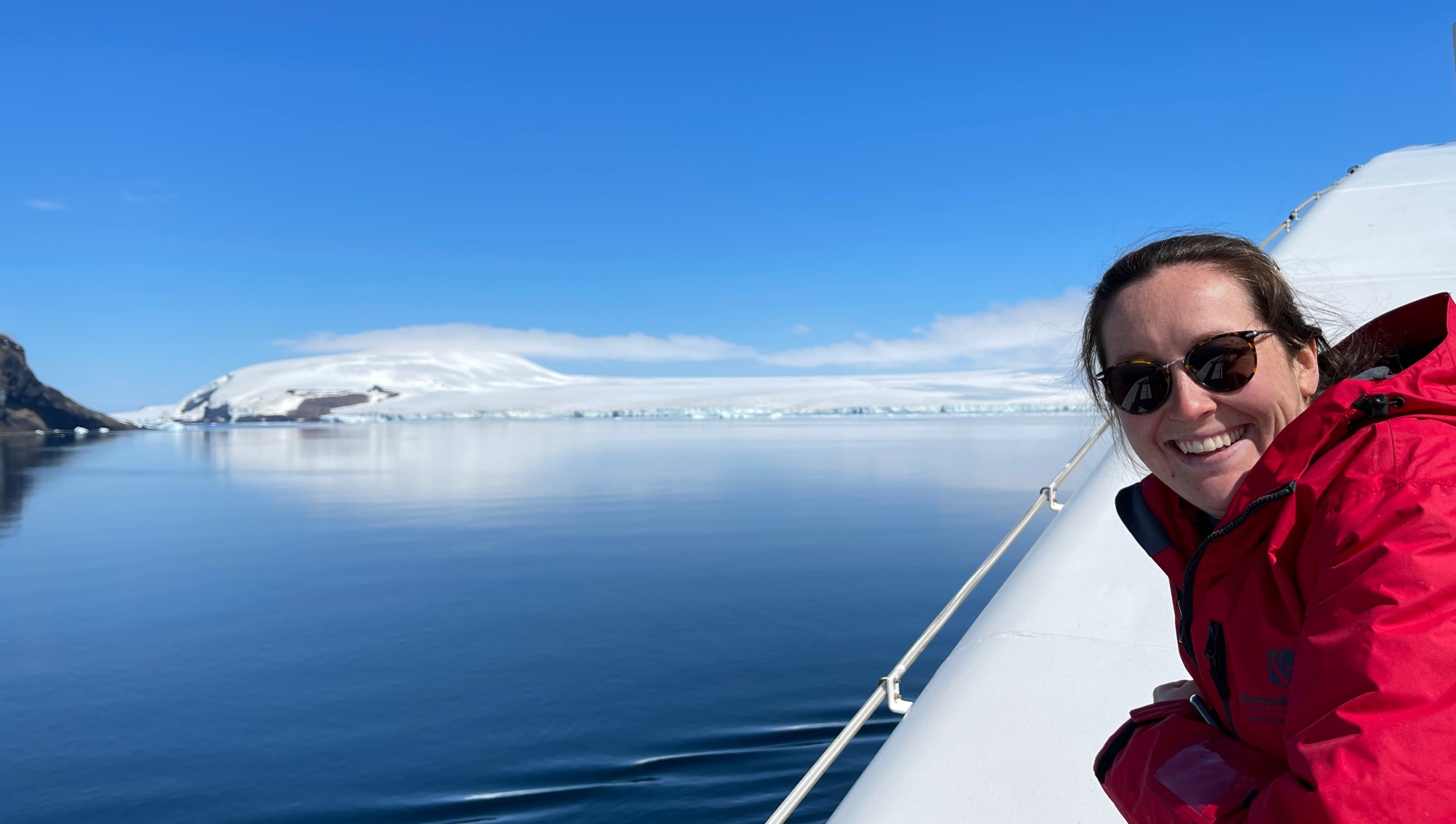 A woman smiles for the camera while sailing in Antarctica 