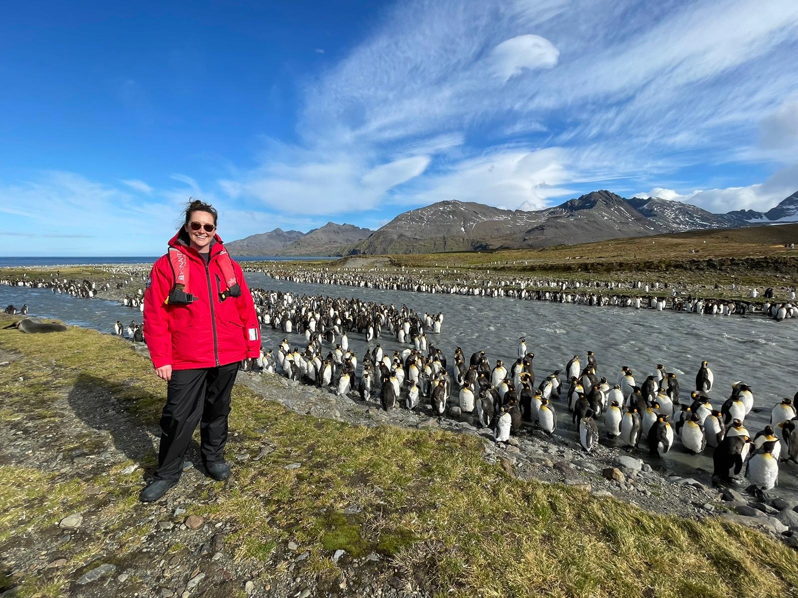 A woman stands in front of hundreds of penguins in South Georgia