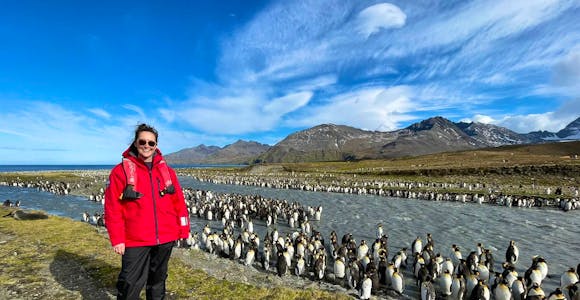 A woman stands in front of hundreds of penguins in South Georgia