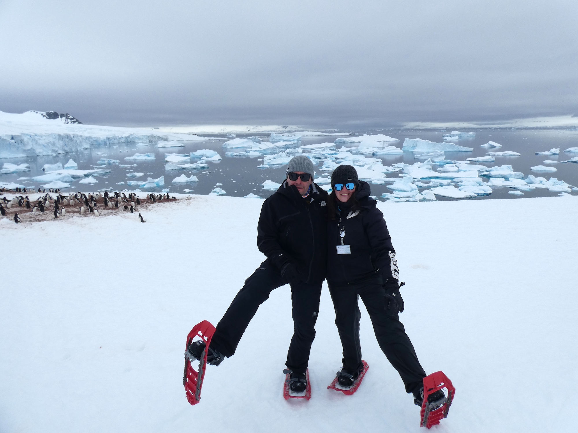 A man and a woman show off their snowshoes in Antarctica 
