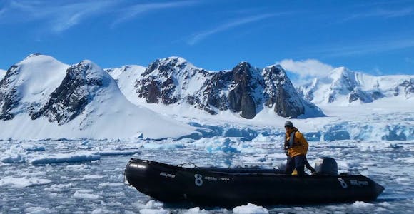 An expedition guide piloting a solo zodiac in Antarctica