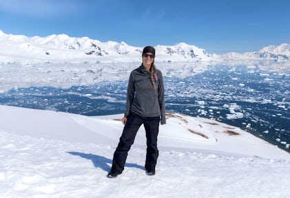 A woman smiles for the camera as she poses in Antarctica