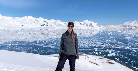 A woman smiles for the camera as she poses in Antarctica