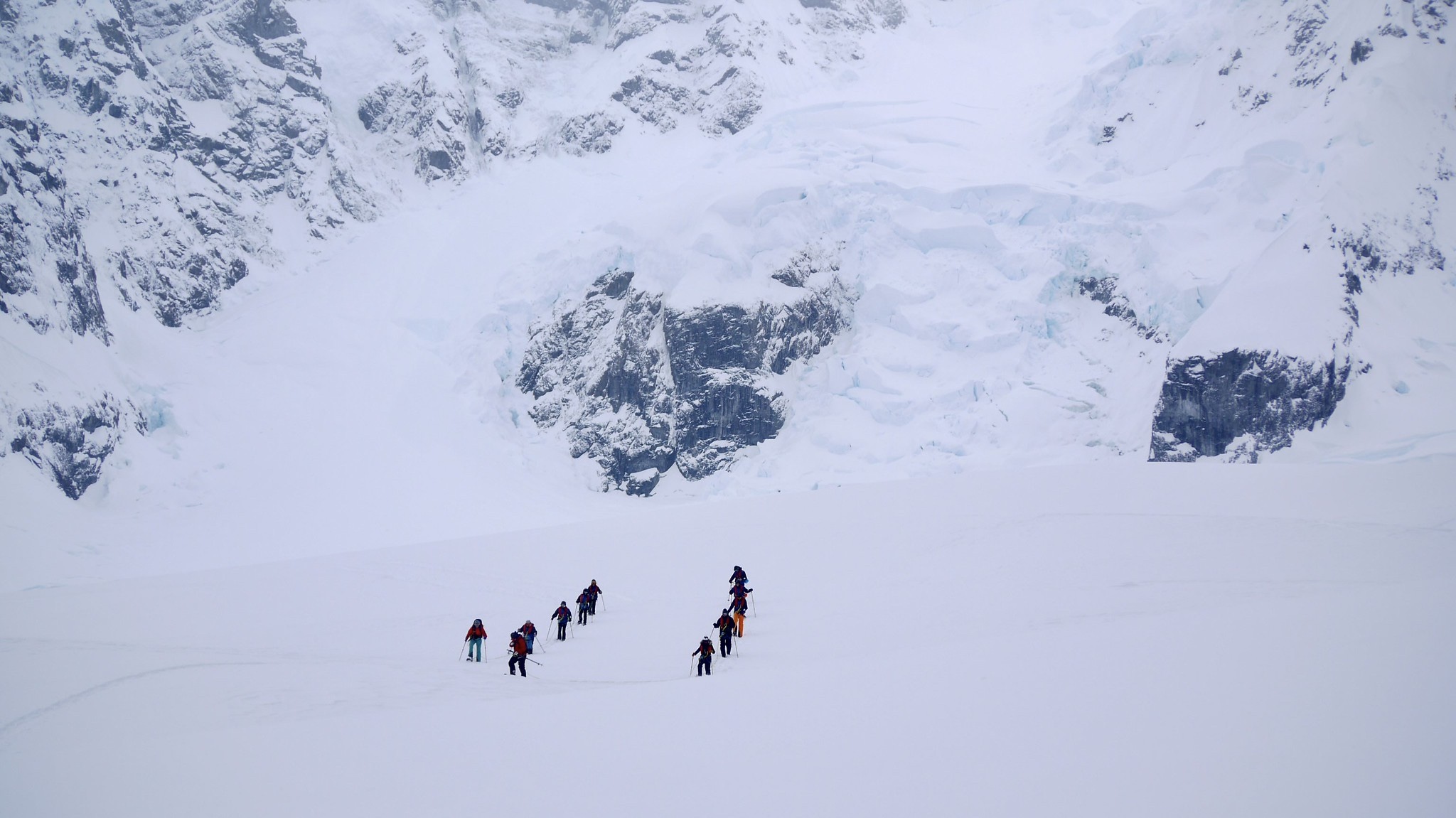 Snowshoers walk across a mountainous, snowy part of Antarctica