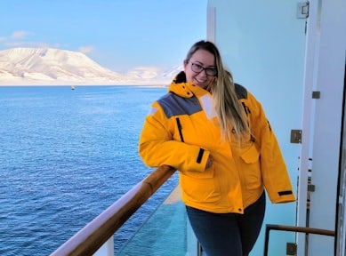 A woman poses on a ship in Antarctica