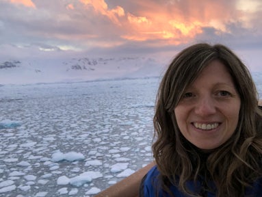 Woman in Antarctica surrounded by brash ice and sunset skies