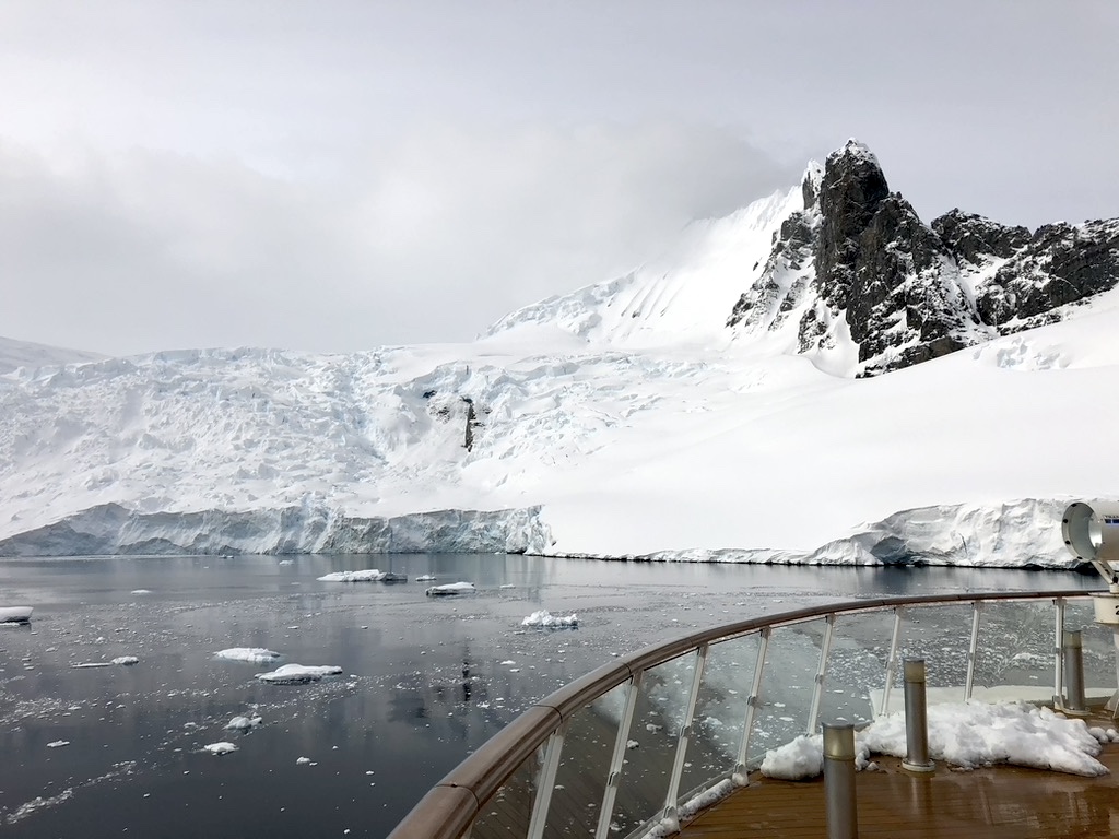 The bow of a ship as it sails through the gloriously still water of the Lemaire Channel