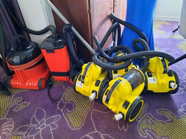 Six yellow and red hoovers/vacuum cleaners ready to clean passengers bags and jackets for Antarctica biosecurity checks