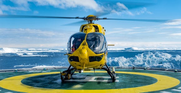 A helicopter takes off from a helipad on board a ship in Antarctica