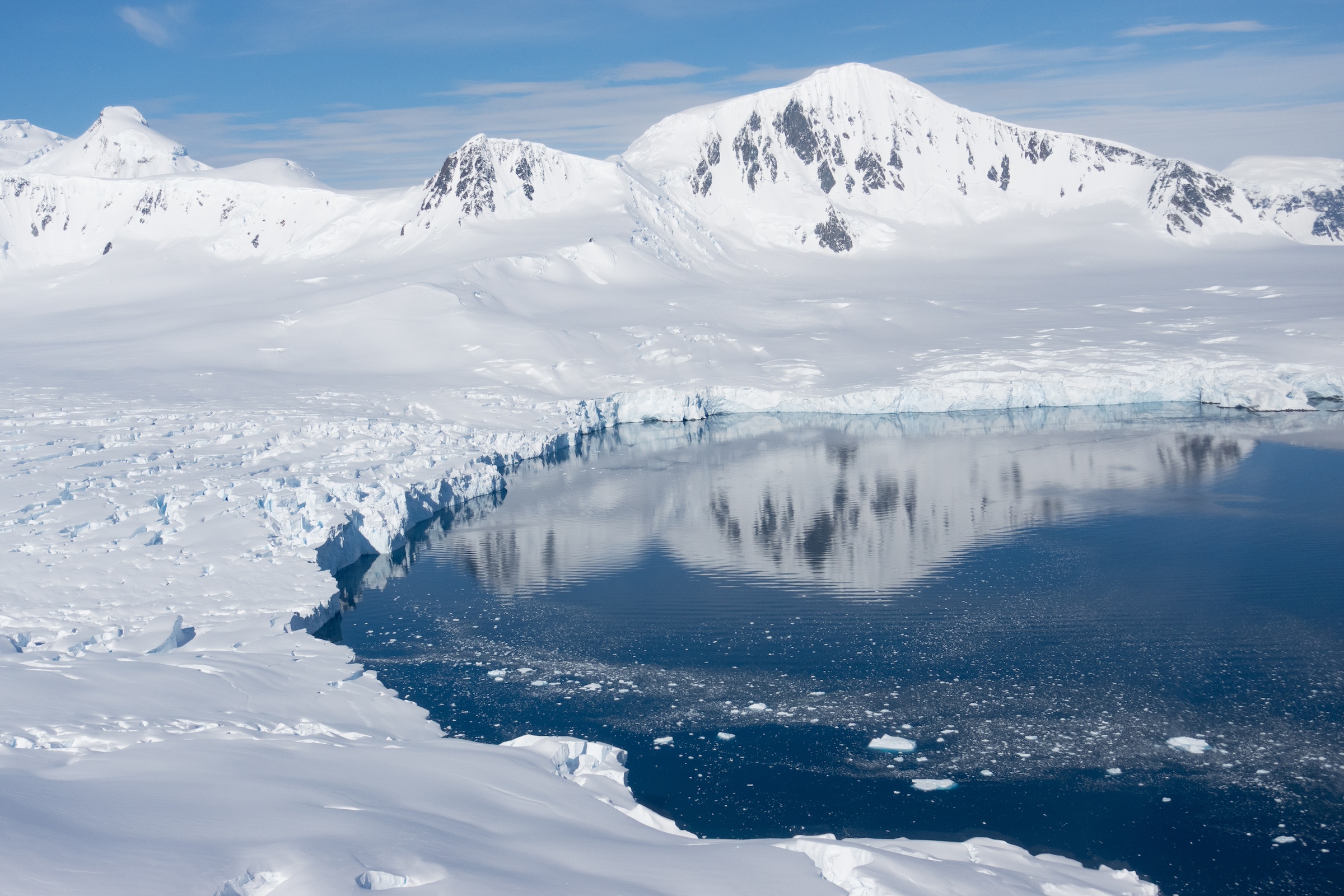 A bird's eye view of Antarctic scenery reflecting in a blue pool of water