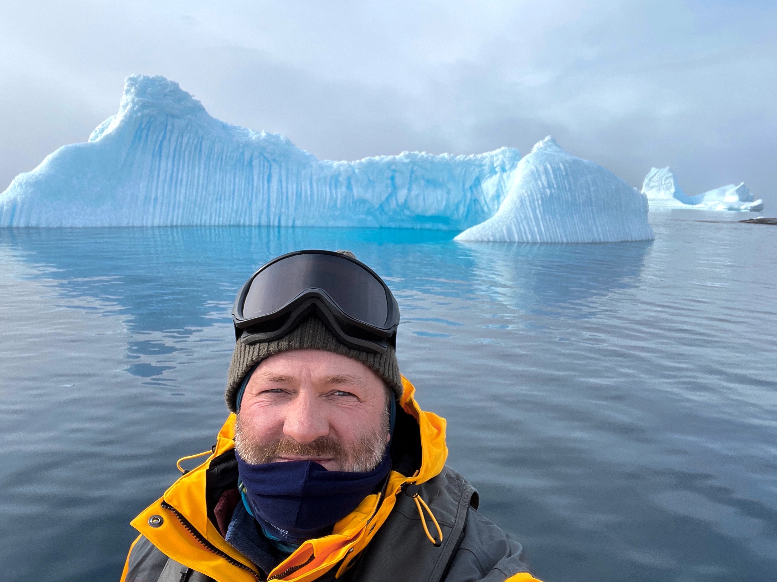 A man takes a selfie with beautiful blue ice in the background in Antarctica 