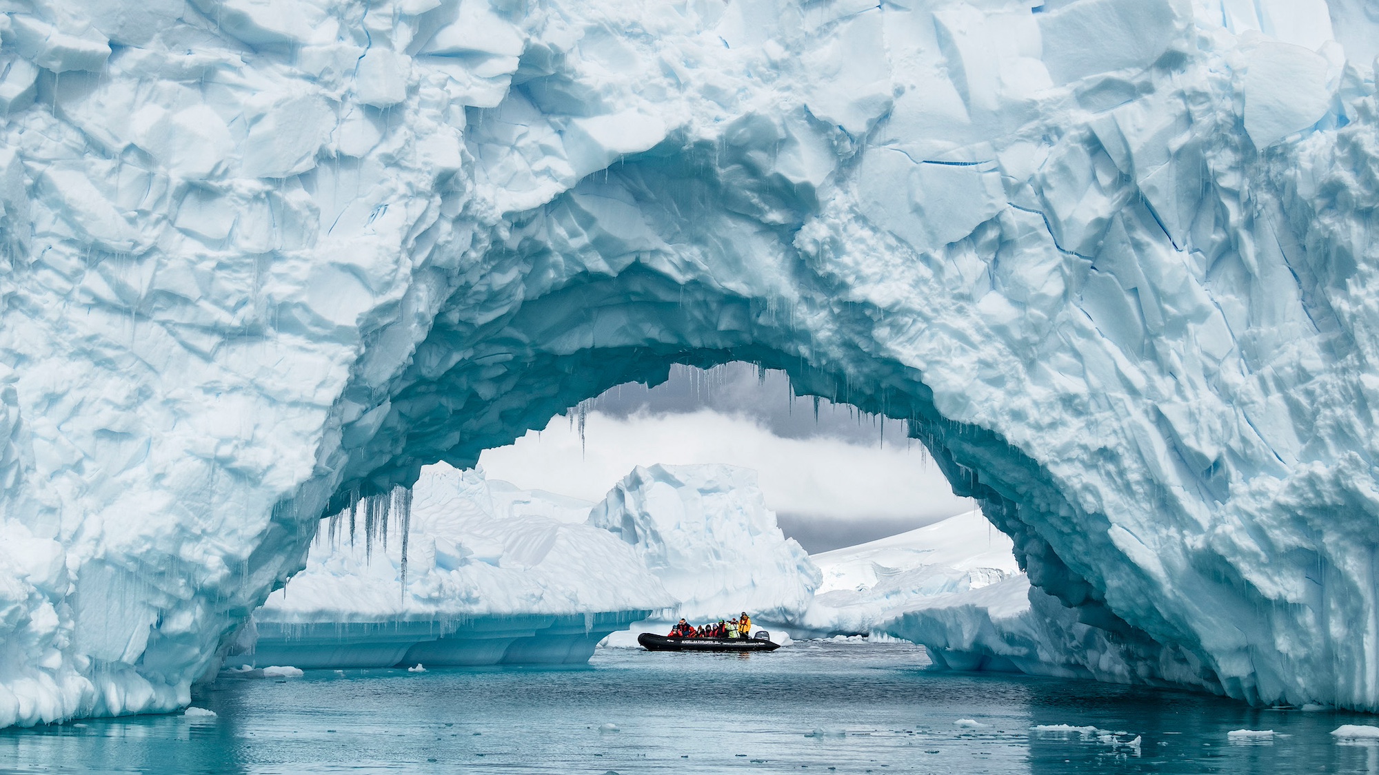 A zodiac through an iceberg arch